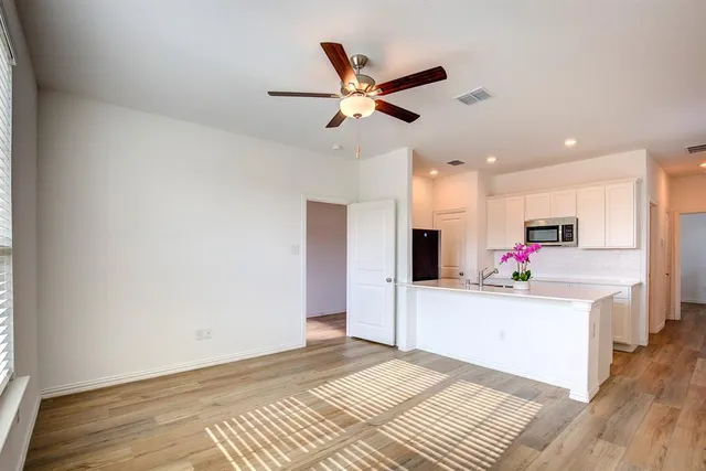 a view of a kitchen with kitchen island wooden floor and a ceiling fan