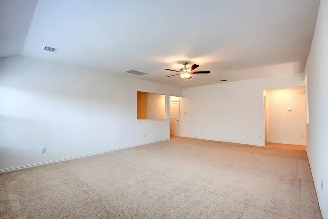 a view of an empty room with a chandelier fan