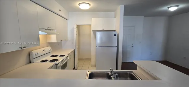 a kitchen with a refrigerator sink and white cabinets
