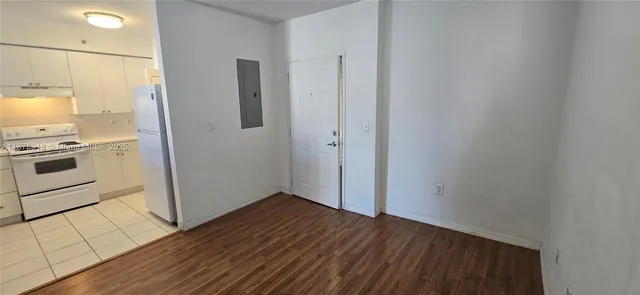 an empty room with wooden floor cabinets and entryway
