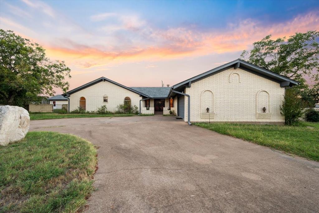Ranch-style house with driveway and brick siding