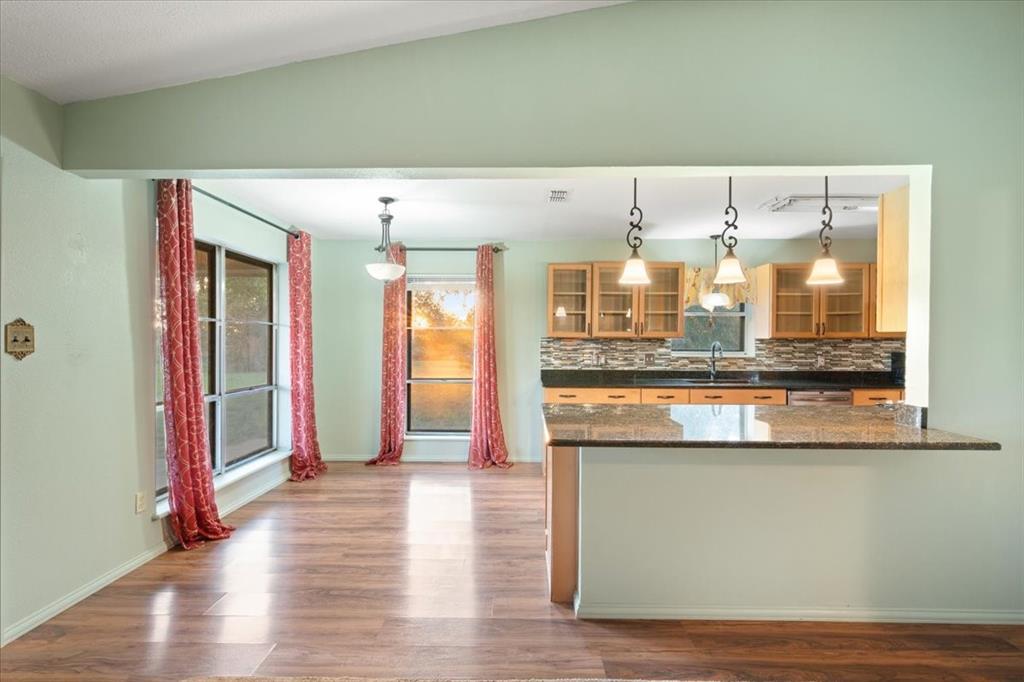 105 Riverside Drive Mineral Wells, TX 76067 - Photo 11 of 40 Kitchen featuring decorative backsplash, hanging light fixtures, light wood finished floors, glass insert cabinets, and dark stone counters