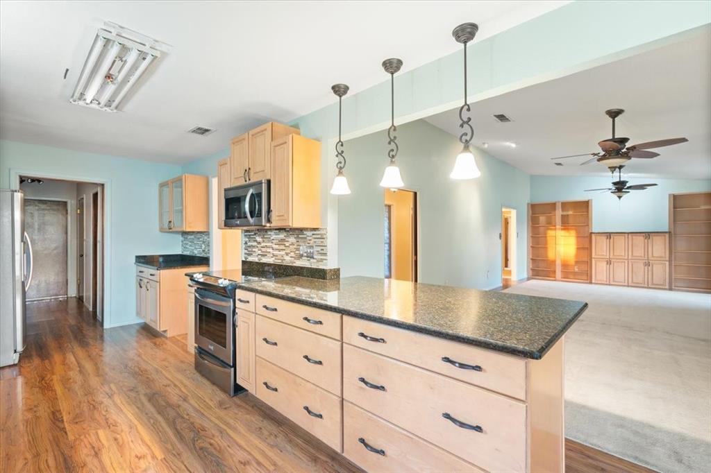 105 Riverside Drive Mineral Wells, TX 76067 - Photo 12 of 40 Kitchen with glass insert cabinets, tasteful backsplash, and hanging light fixtures
