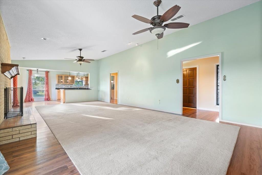 105 Riverside Drive Mineral Wells, TX 76067 - Photo 8 of 40 Unfurnished living room with lofted ceiling, wood finished floors, a fireplace, and a ceiling fan
