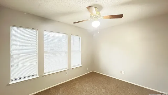 an empty room with a window and a fan
