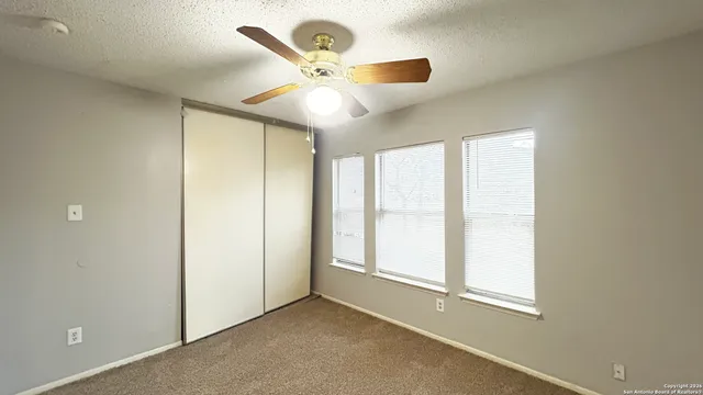 an empty room with windows and fan