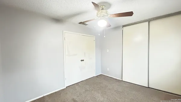 an empty room with a window and a fan