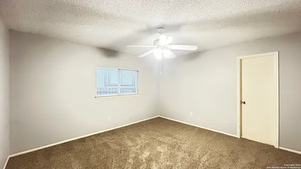 an empty room with a ceiling fan and a window
