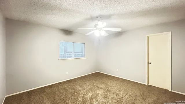 an empty room with a ceiling fan and a window