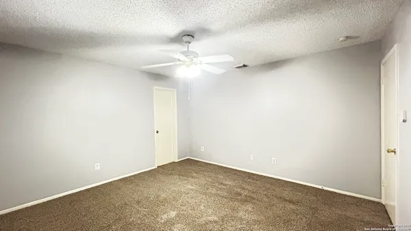 an empty room with a ceiling fan and a fan