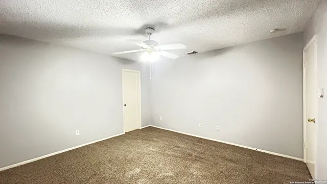 an empty room with a ceiling fan and a fan