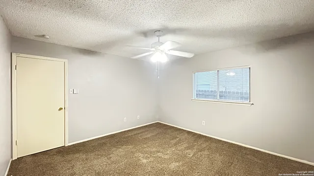 an empty room with a ceiling fan and a window