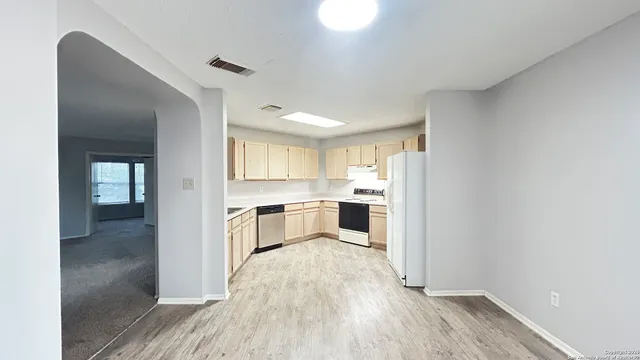 a large white kitchen with a sink and refrigerator