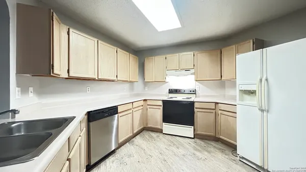 a kitchen with granite countertop a sink stove and refrigerator