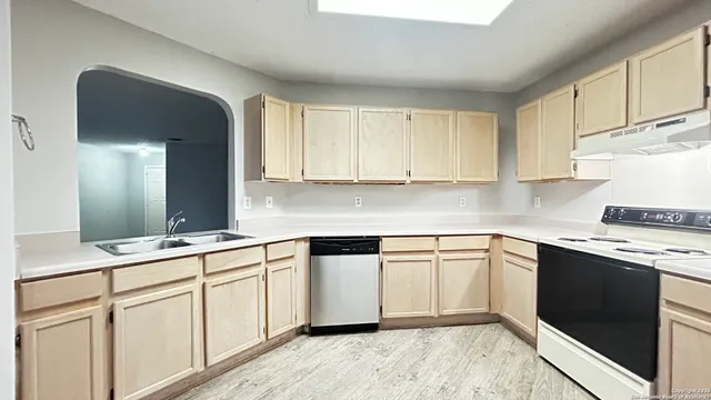 a kitchen with white cabinets appliances and a sink
