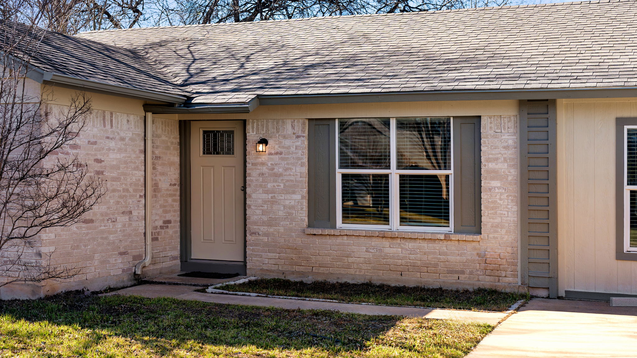 View of exterior entry with brick siding and roof with shingles. One Story | 4 bedrooms & 2 full bathrooms