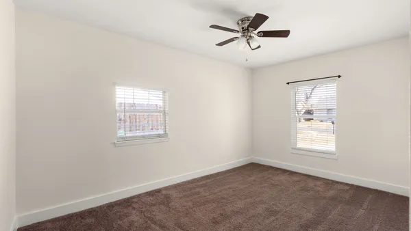 an empty room with a ceiling fan and window