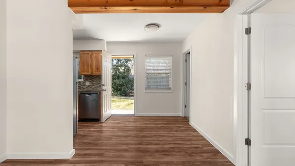 a view of a hallway with wooden floor and a bathroom