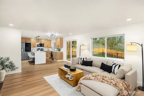 a large living room with stainless steel appliances kitchen island granite countertop a couch and a view of kitchen living room