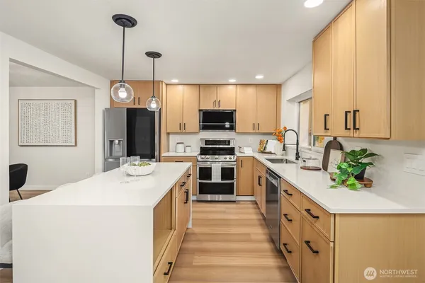 a kitchen with stainless steel appliances kitchen island granite countertop a sink a stove top oven a counter space and cabinets