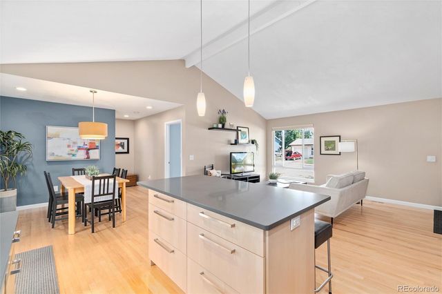 a kitchen with a dining table chairs wooden floor and appliances