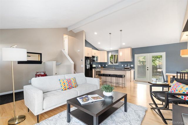 a living room with furniture kitchen view and a wooden floor