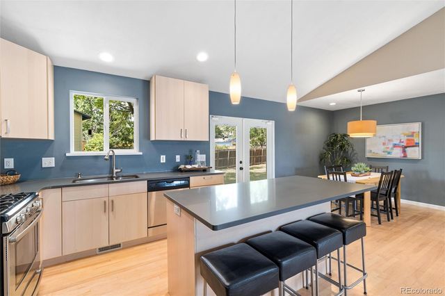 a kitchen with a stove a sink a kitchen island with chairs and wooden cabinets