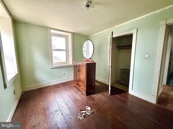 an empty room with wooden floor mirror and windows
