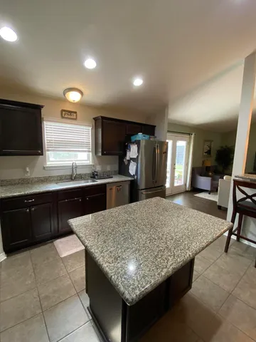 a kitchen with granite countertop kitchen island stainless steel appliances a sink stove top oven and granite counter tops