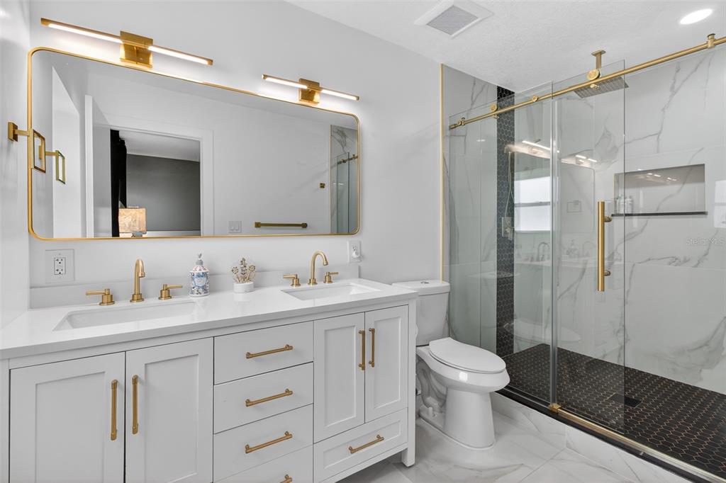1714 Indian Rocks Road Belleair, FL 33756 - Photo 28 of 62 a bathroom with a double vanity sink toilet mirror and shower
