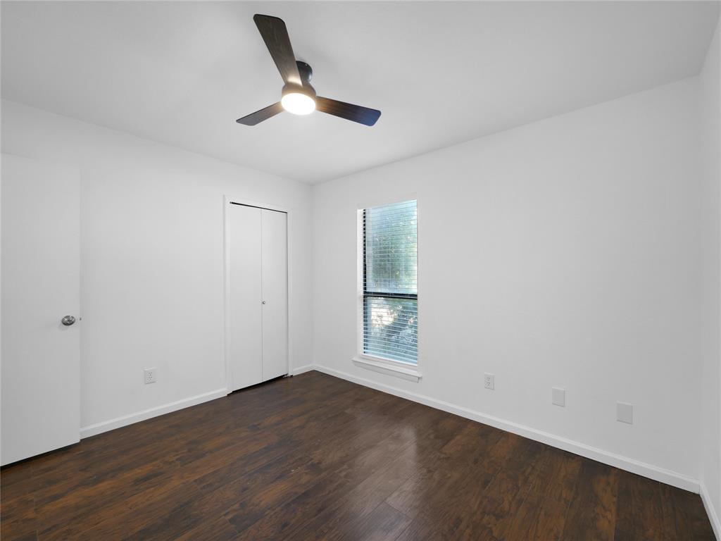 1472 Rockshire Drive Plano, TX 75074 - Photo 22 of 27 Dark wood-finish flooring, white walls, ceiling fan with integrated lighting, window with blinds, and white bi-fold closet doors