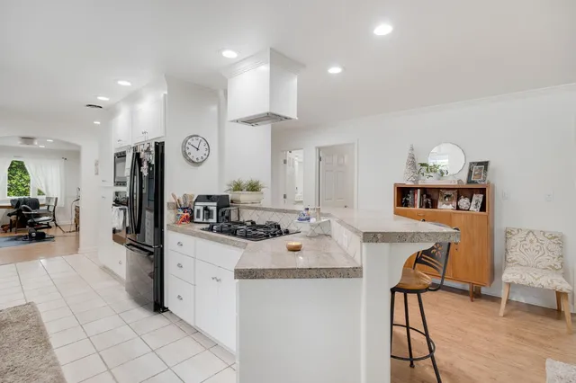 a large white kitchen with a sink and dishwasher a stove top oven with wooden floor