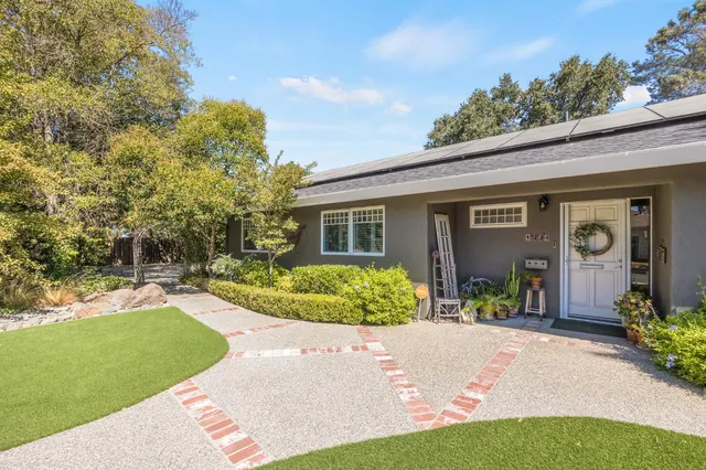 a living room with stainless steel appliances furniture a rug and a kitchen view