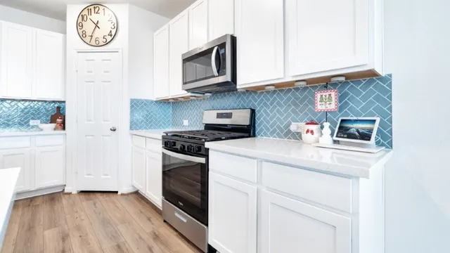 a kitchen with stainless steel appliances a sink a stove a microwave a refrigerator a sink and cabinets