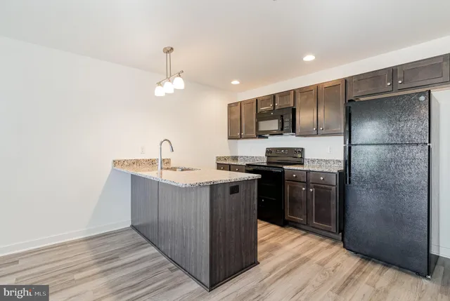 a kitchen with stainless steel appliances granite countertop a refrigerator a sink a stove and oven