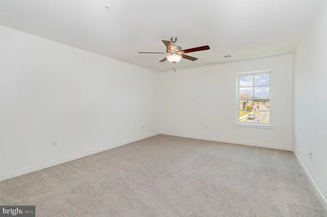 an empty room with a window and ceiling fan