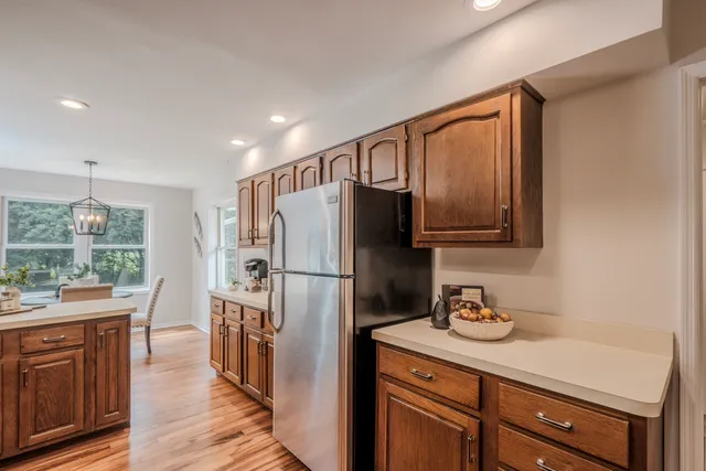 a kitchen with stainless steel appliances granite countertop a refrigerator a sink dishwasher and wooden cabinets with wooden floor