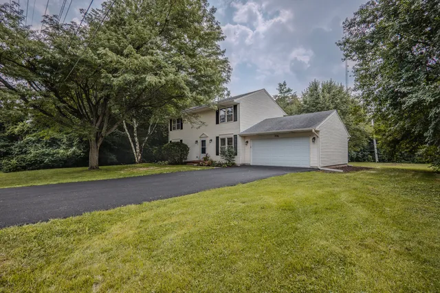 a front view of house with yard and trees in the background