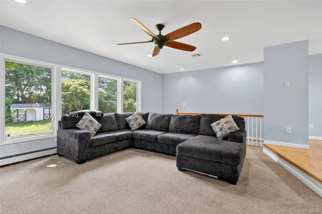 a living room with furniture and a large window with a ceiling fan