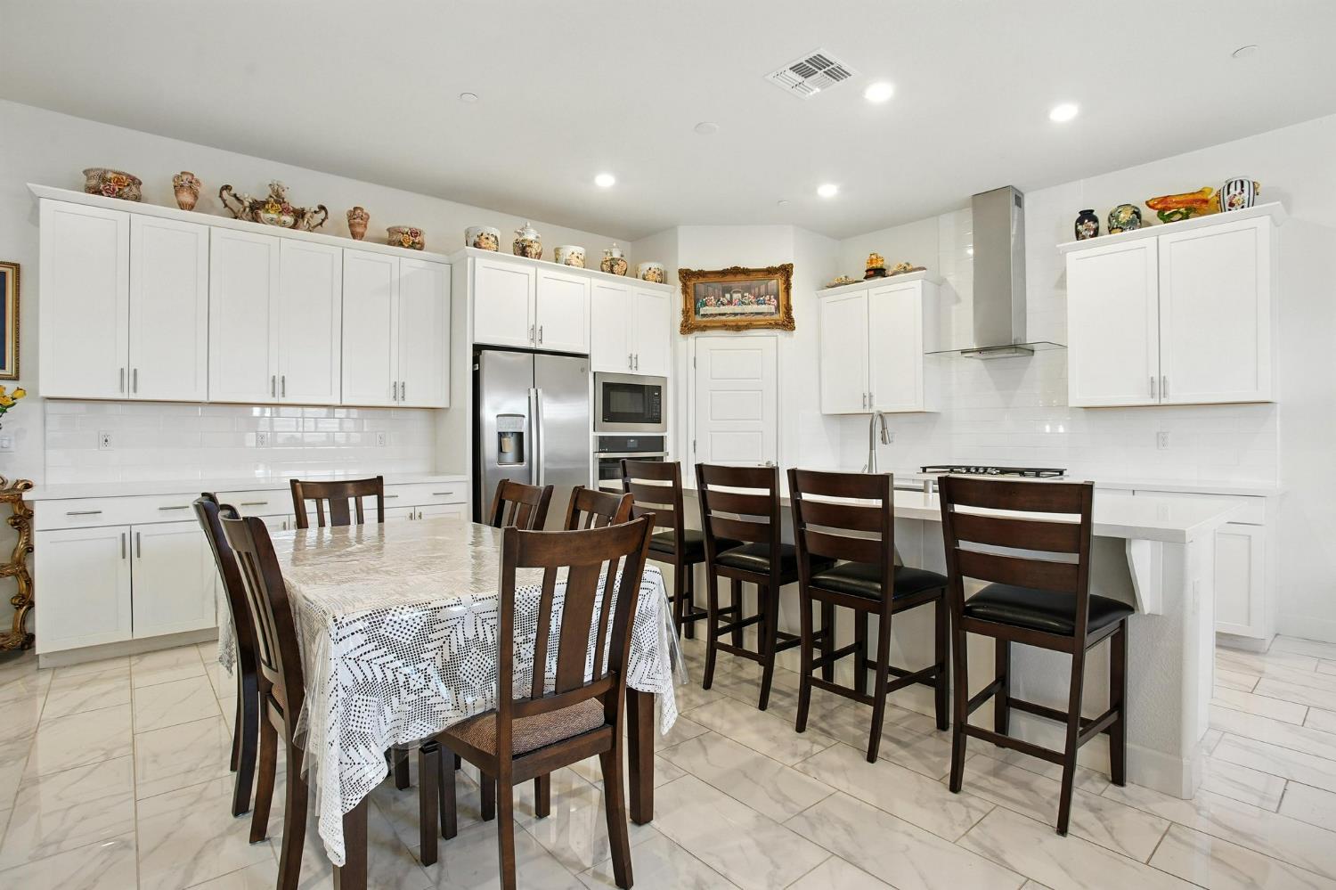 3742 Haymaker Way Sacramento, CA 95835 - Photo 12 of 39 a kitchen with stainless steel appliances kitchen island granite countertop a dining table chairs and a refrigerator