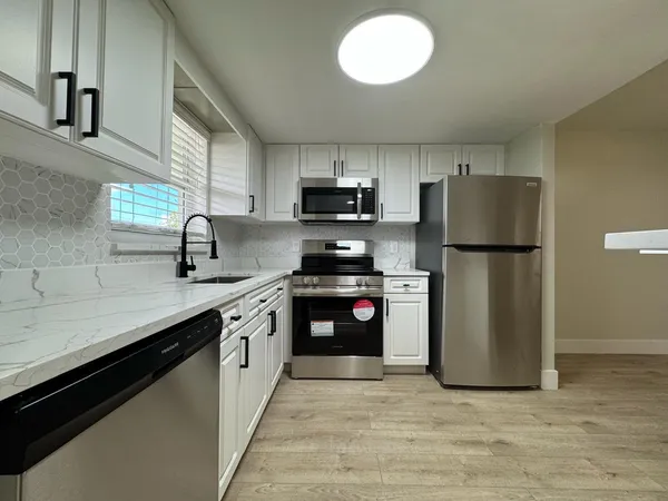 a kitchen with granite countertop a refrigerator and a sink