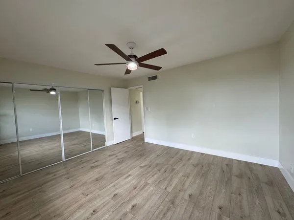 an empty room with wooden floor and a ceiling fan