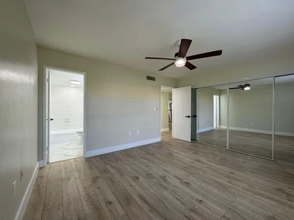 a view of empty room with wooden floor and fan