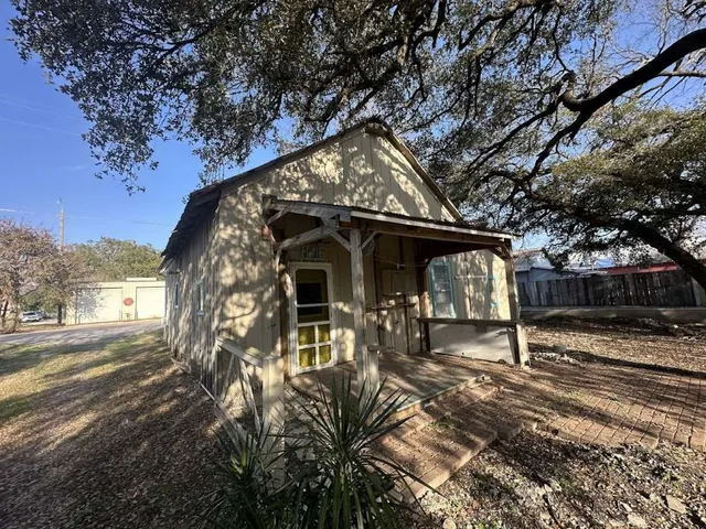 a view of house with yard outdoor seating and covered with trees