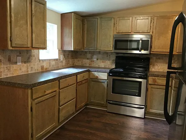 a kitchen with granite countertop white cabinets stainless steel appliances and wooden floor