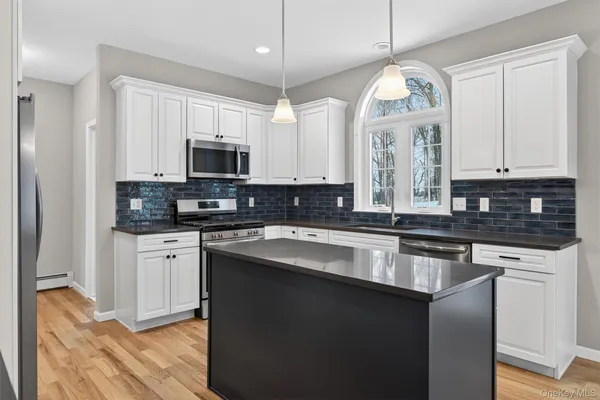 a kitchen with stainless steel appliances granite countertop a stove a sink and a microwave