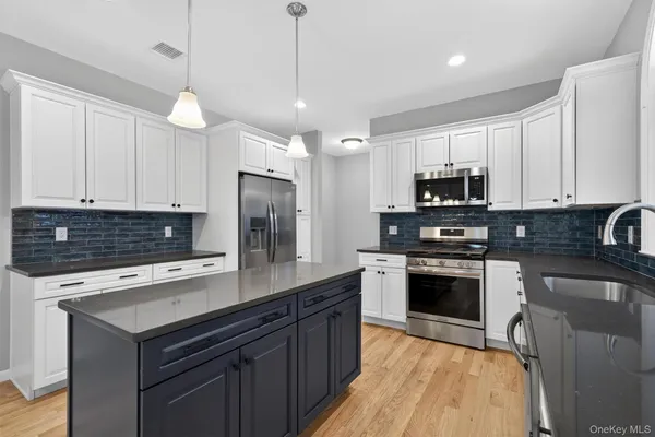 a kitchen with kitchen island granite countertop a sink cabinets and stainless steel appliances