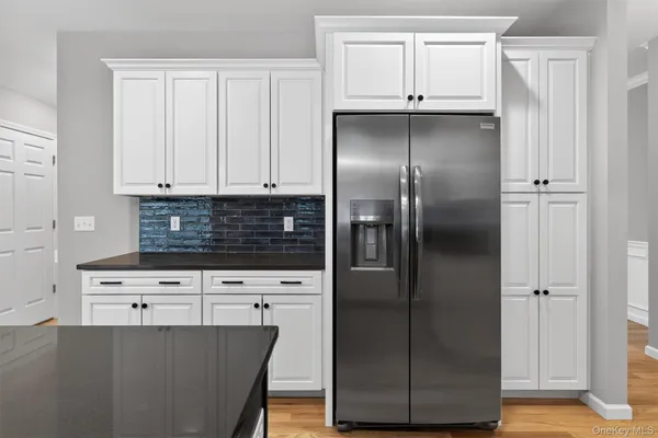 a kitchen with stainless steel appliances granite countertop a refrigerator a stove and a cabinets with wooden floor