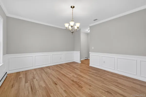 a view of an empty room with wooden floor and a chandelier