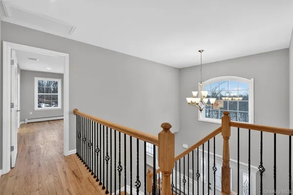 a view of a hallway with wooden floor and chandelier